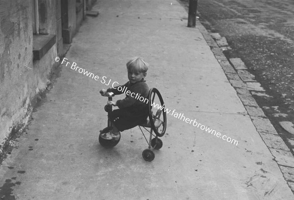 CHILD ON TRICYCLE IN STREET